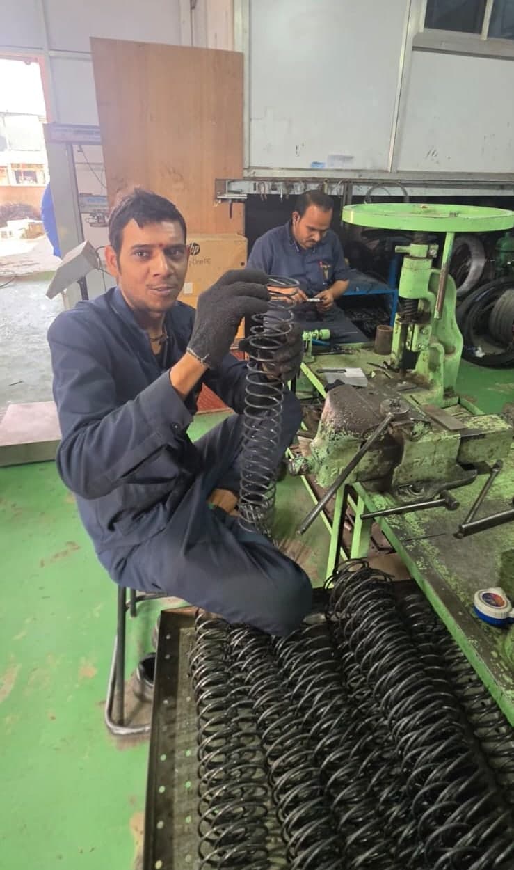 Spring Tech team member with a batch of finished compression springs